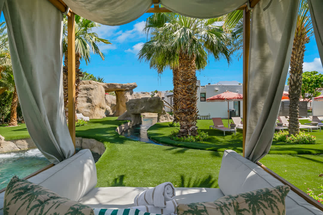 A shaded cabana looking out over the lazy river and palm trees