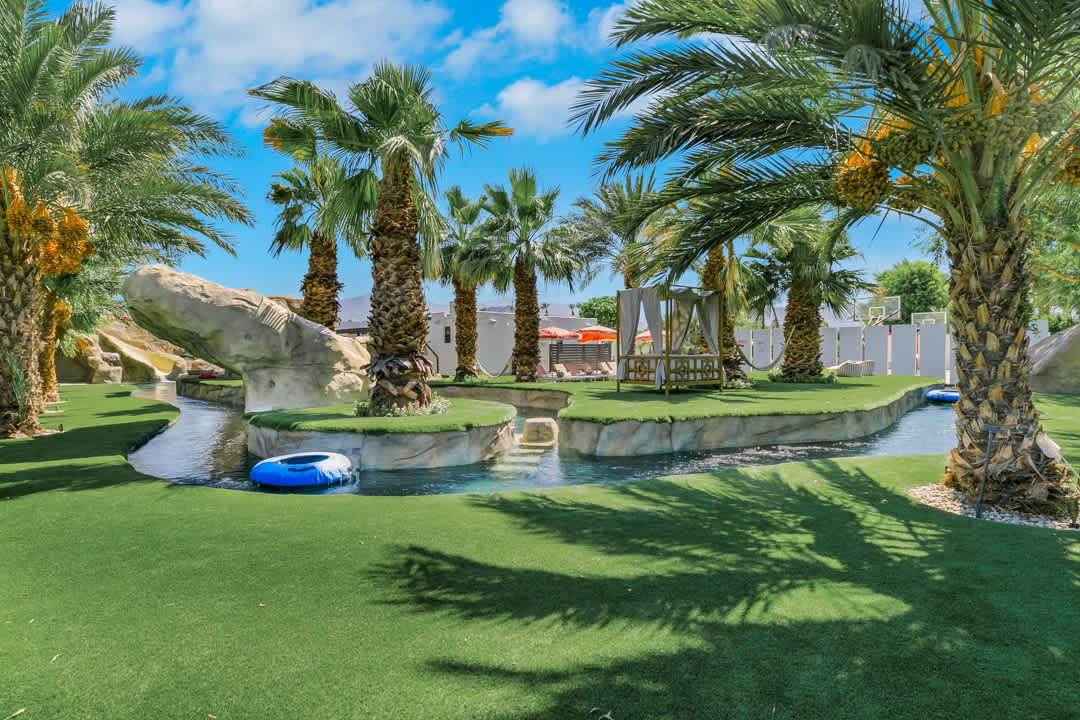The lazy river and green lawn beneath palm trees