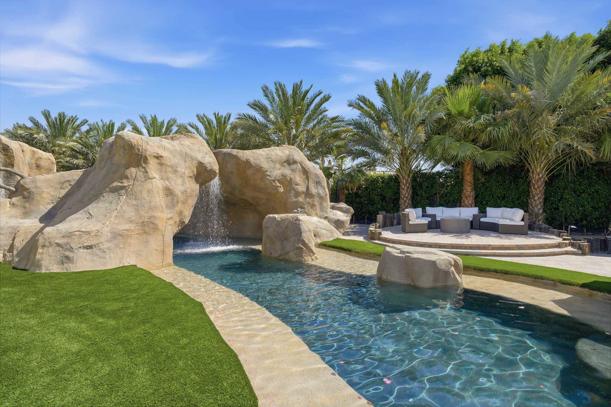 The lazy river winding past a waterfall grotto and palms at Wandery Ranch